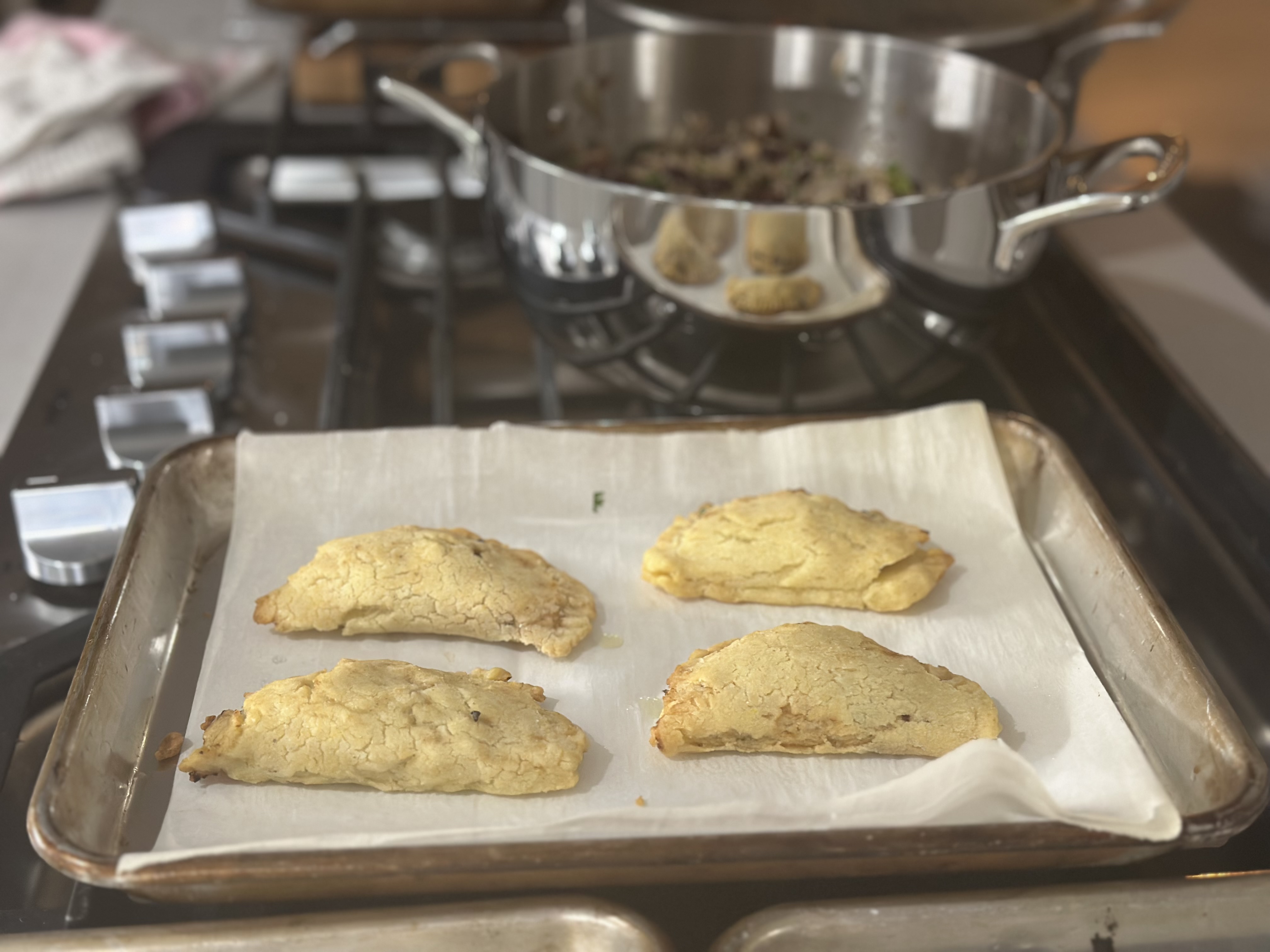 Four golden-baked mushroom, white bean, and sweet potato empanadas on a parchment-lined tray