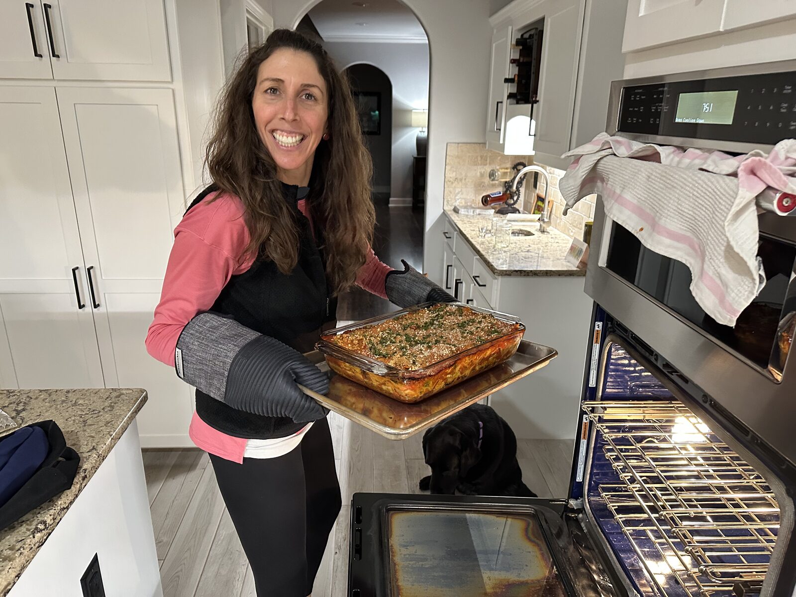 Katie smiling and holding a fresh-baked vegetable lasagna in her kitchen